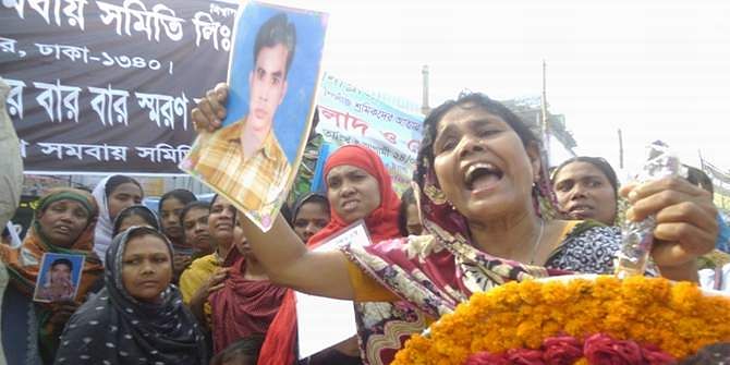 Mother of a Rana Plaza victim holds her son's photograph in her hand as she carries a wreath to place it at a monument in Savar erected in commemoration of all those people who lost their lives. She did not find her son's body since then. Photo: Star