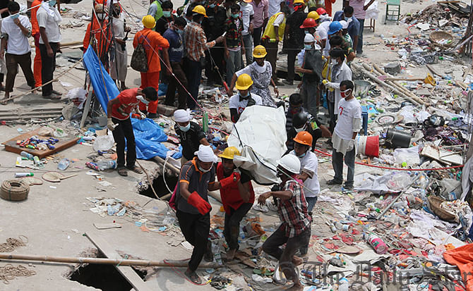 Volunteers bring out a body from the rubble of Rana Plaza after cutting a hole on the rooftop of the collapsed building. Photo: Star