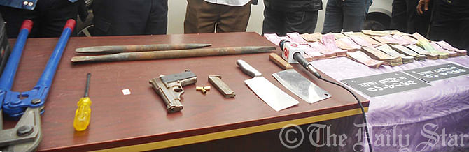 Law enforcers produce a pistol, 10 sharp weapons, looted money, a private car (not seen in the photo) and other equipment used to break locks before reporters after they were seized from the procession of a robber gang in Mithapukur upazila of Rangpur.