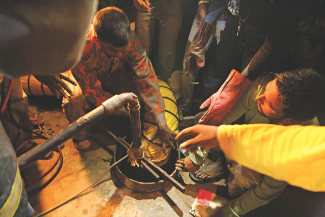 Rescuers pump in oxygen into the well shaft using a pipe and try to get a child, who had fallen in the shaft, out by tying a sack at the end of a rope and lowering it in at Shahjahanpur Railway Colony in Dhaka on Friday. Photo: STAR