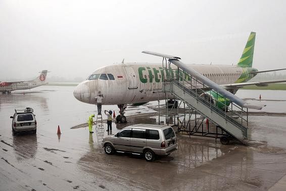 Workers stand near a Citilink airplane covered with ash from Mount Kelud at Adi Sucipto airport in Yogyakarta February 14, 2014. Photo: Reuters
