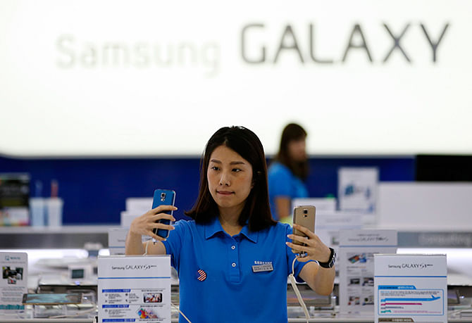 A sales assistant checks Samsung Electronics' Galaxy S5 smartphones at a shop in Seoul July 29, 2014. Photo: Reuters