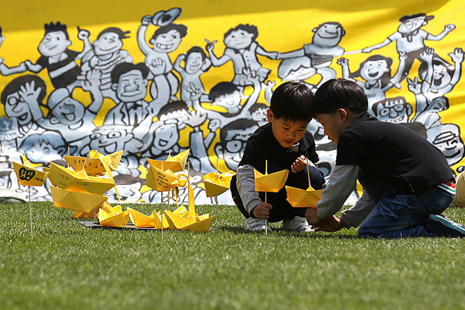 Children play with yellow coloured paper ships near a memorial altar for victims onboard passenger ship Sewol set up at Seoul City Hall Plaza on Sunday. A culture of cosy personal ties that can blur the lines between businesses and those regulating them, of profit over safety, and soft courts is in focus as South Korea demands answers over the sinking of a ferry with the loss of more than 300 lives, mainly high school students. Photo: Reuters