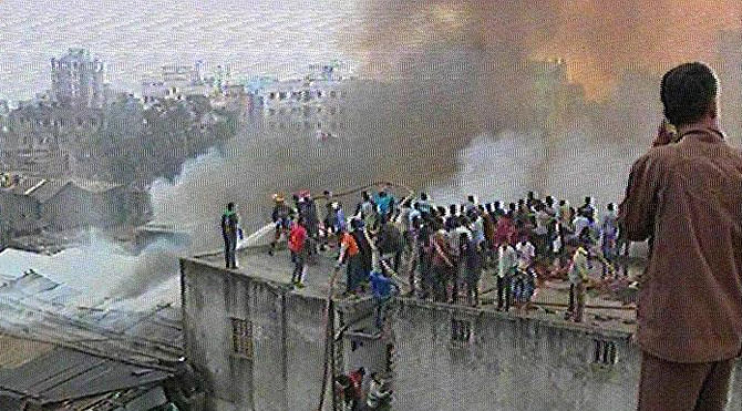 Smoke coming out from the shanties at a slum at Battala Katasur in Dhaka’s Mohammadpur area after fire breaks out there on Sunday morning. Photo: TV grab