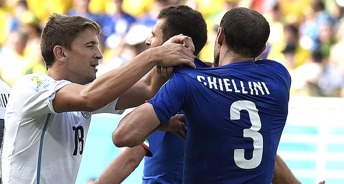 Italy's defender Giorgio Chiellini (R) attempts to show a bite mark by Uruguay striker Luis Suarez as Uruguay midfielder Gaston Ramirez pulls his shirt up during a Group D football match between Italy and Uruguay at the Dunas Arena in Natal during the 2014 FIFA World Cup on June 24, 2014. Photo: AFP/Getty Images 