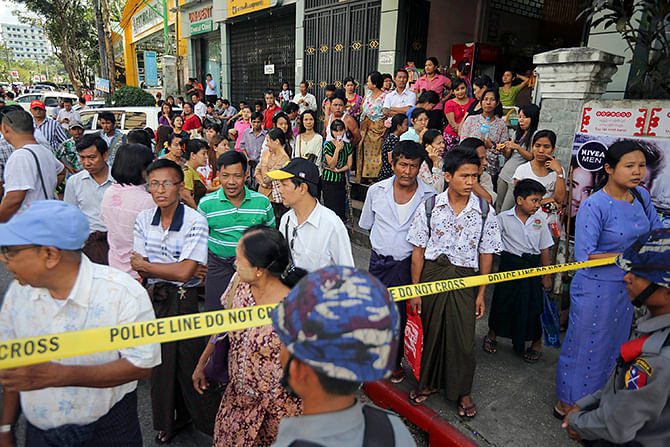 Policemen secure the road as people wait to get a glimpse of US President Barack Obama's convoy passing near the house of opposition politician Aung San Suu Kyi in Yangon November 14, 2014.