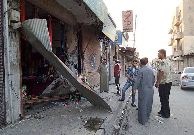 People inspect a shop damaged after what Islamist State militants say was a US drone crashed into a communication station nearby in Raqqa September 23, 2014. The United States and several Gulf Arab allies launched air and missile strikes on Islamic State strongholds in Syria on Tuesday, US officials said, opening a new, far more complicated front in the battle against the militants. Photo: Reuters