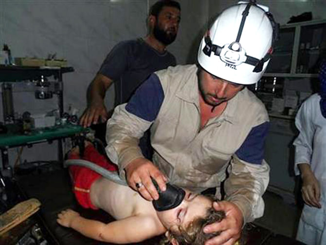 In this photo posted on August 28, 2014, provided by Civil Defense Idlib, a group of volunteers in northern Syria which has been authenticated based on its contents and other AP reporting, show a Syrian civil defense worker with his white helmet, treats a girl, in Idlib province, northern Syria. Photo: AP