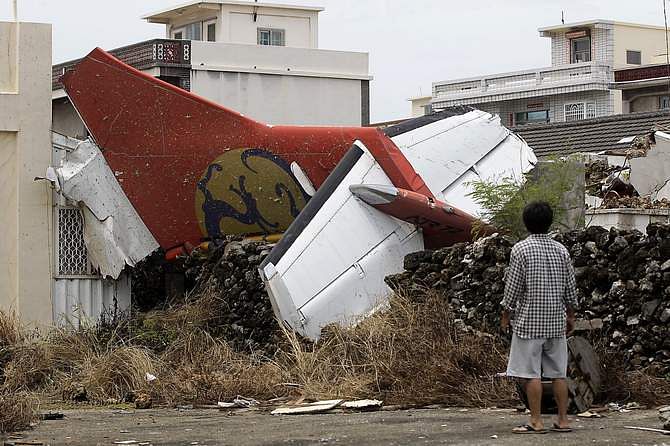 A man stands in his backyard and looks at the wreckage of a TransAsia Airways turboprop plane that crashed on Taiwan's offshore island Penghu July 24, 2014. The leaders of rivals China and Taiwan expressed condolences on Thursday for victims of the plane that crashed during a thunderstorm the previous day killing 48 people including two French nationals. Photo: Reuters