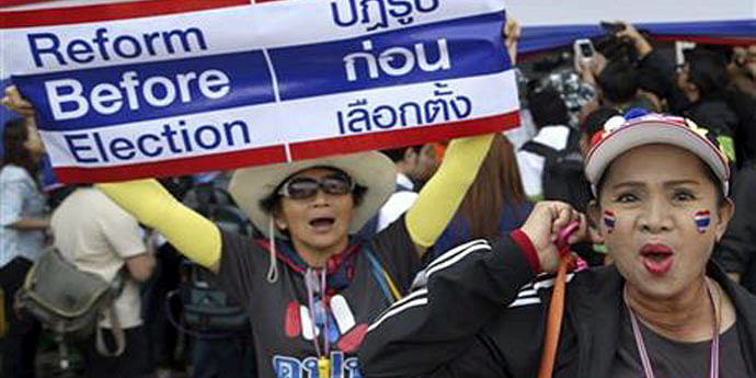An anti-government protester sits next to a portrait of Thailand's King Bhumibol Adulyadej as she camps outside the Thai-Japan youth stadium, along with other demonstrators, in Bangkok December 24, 2013. 