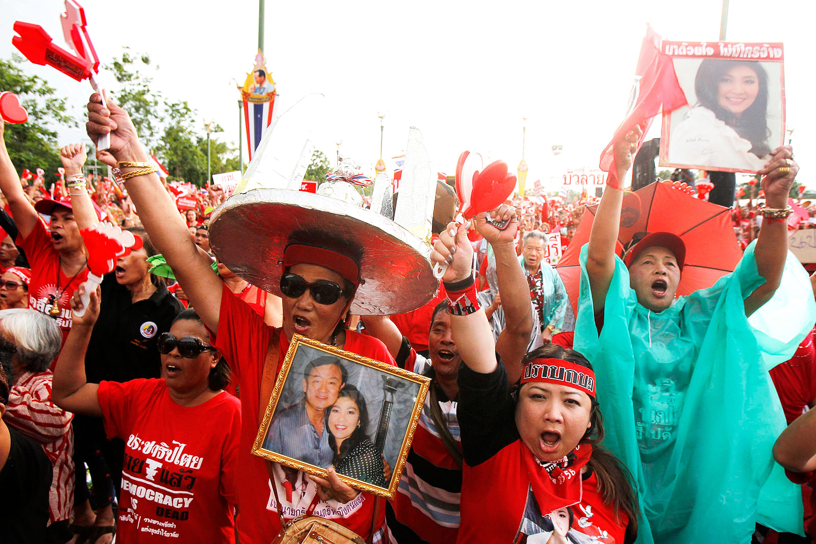 A member of the pro-government "red shirt" group gestures while holding a picture of ousted Thai Prime Minister Yingluck Shinawatra and her brother Thaksin during a rally in Nakhon Pathom province on the outskirts of Bangkok, May 11, 2014. Photo: Reuters