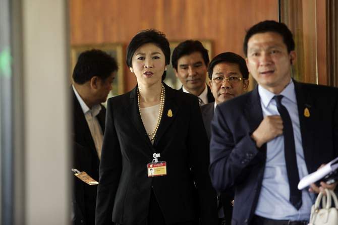 Yingluck Shinawatra, Thailand's prime minister, second left, reacts as she leaves Parliament House following a censure vote in Bangkok, Thailand, on Thursday, November 28, 2013. Photo: Getty Images
