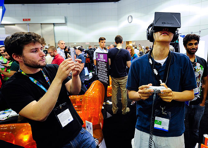 This Reuters photo taken on June 12, 2013 shows software designer Julian Kantor (L), who created "The Recital", takes a picture of Jonathan Feng using the Oculus Rift virtual reality headset to experience his program during E3 in Los Angeles, California. Facebook Inc will acquire two-year-old Oculus VR Inc, a maker of virtual-reality glasses for gaming, for $2 billion, buying its way into the fast-growing wearable devices arena with its first-ever hardware deal. On March 25, 2014, Facebook said virtual-reality technology could emerge as the next social and communications platform. Photo: Reuters