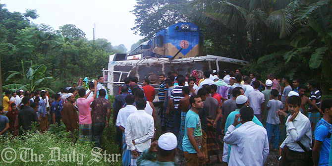 People crowd the accident site where 10 people including two children were killed as a train hit a bus carrying a wedding party while it was crossing the rail lines at Barobazar of Kaliganj upazila in Jhenidah early Friday. Photo Star