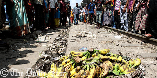 YET ANOTHER LIFE LOST ON THE TRACKS: People gather around a basket full of bananas by the rail track after its owner was hit by a train at Karwan Bazar in the capital on Thursday. Vendors and hawkers selling their goods on the rail lines are a common scenario all over the country.  Photo: Anisur Rahman