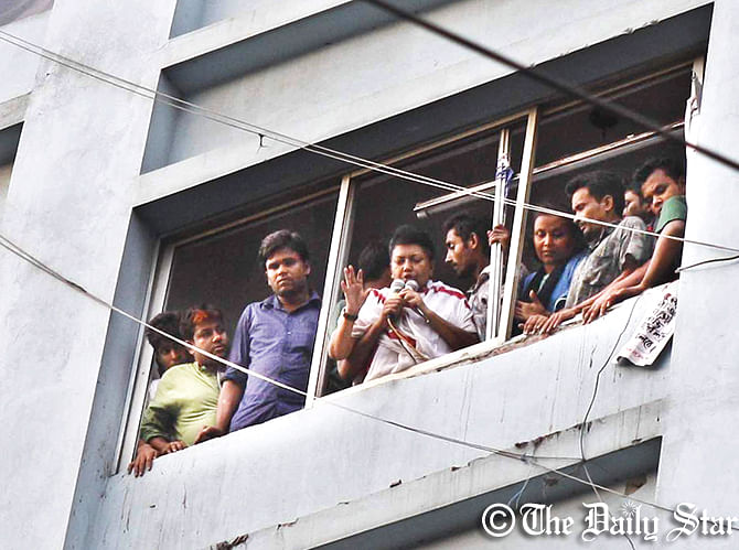 Agitating garment workers of Tuba Group make the strike announcement through a loud speaker from a sixth floor window of a factory at Hossain Market in Badda of Dhaka on Wednesday. They could not meet media due to restrictions by law enforcers. Photo: Amran Hossain
