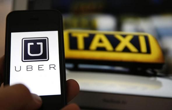 An illustration picture shows the logo of car-sharing service app Uber on a smartphone next to the picture of an official German taxi sign in Frankfurt, September 15, 2014. Photo: Reuters