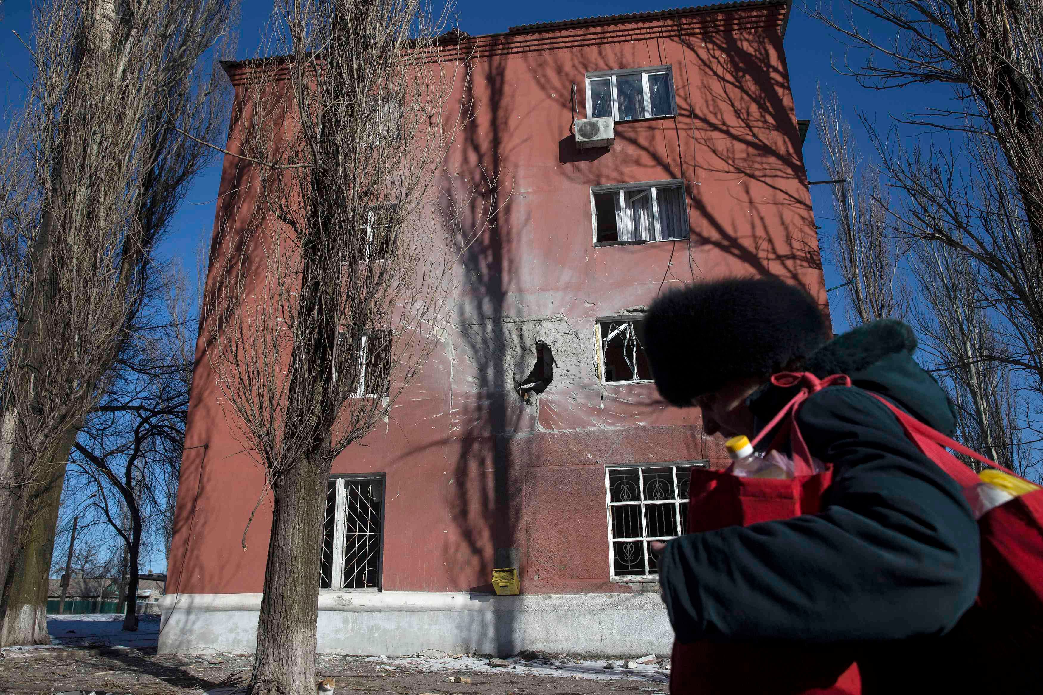 A woman walks past a house damaged by fighting in the town of Vuhlehirsk near Debaltseve February 18, 2015. Photo: REUTERS