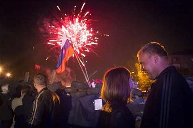 People watch fireworks celebrating the declaration of independence for Donetsk region at barricades in front of a regional administration building that was recently seized by pro-Russian activists in Donetsk, Ukraine, Monday, May 12, 2014, with a Russian national flag is in the background. Photo: AP