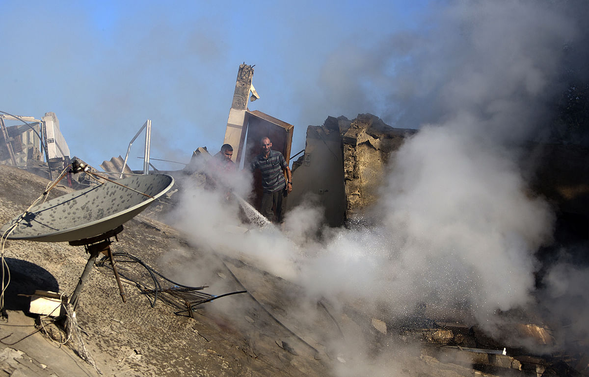 A Palestinian firefighter tries to extinguish fire at a house destroyed by an overnight Israeli air strike, on July 16, 2014, in Gaza City. Photo: Getty Images