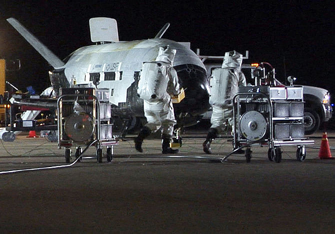 Personnel in self-contained atmospheric protective ensemble suits conduct initial checks on the X-37B Orbital Test Vehicle 1, the U.S. Air Force's first unmanned re-entry spacecraft, after its landing at Vandenberg Air Force Base in California, in this handout photo taken December 3, 2010, courtesy of the U.S. Air Force.