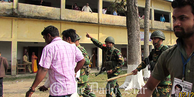 Army men throw out supporters of Awami League-backed chairman candidate, Mostofa Talukdar, from Motlob Degree College Polling Centre in Motlob South upazila of Chandpur Thursday morning. The supporters forcefully occupied the centre during upazila elections. Photo: Star