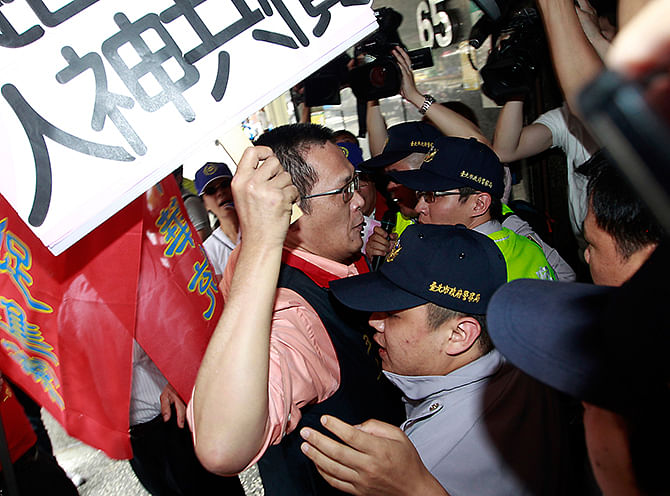 Activists holding placards scuffle with police officers during a protest in front of Vietnam Economic and Cultural office due to the anti-China protest in Vietnam, in Taipei on Thursday. The placard reads, 