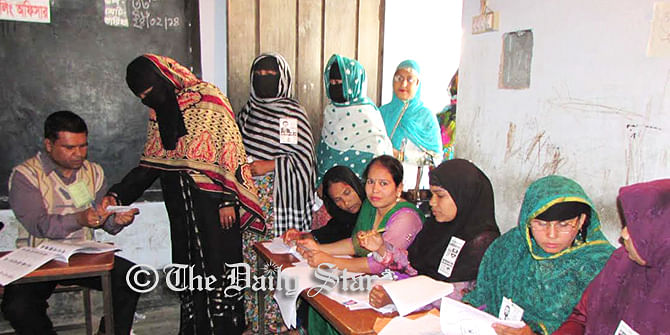 A woman is seen taking ballot to cast her vote while others waiting in a queue in Sabdarkhan Govt Primary School Polling Centre of Chandpur Sadar upazila amid festive mode on the second phase of upazila elections today. Photo: Star
