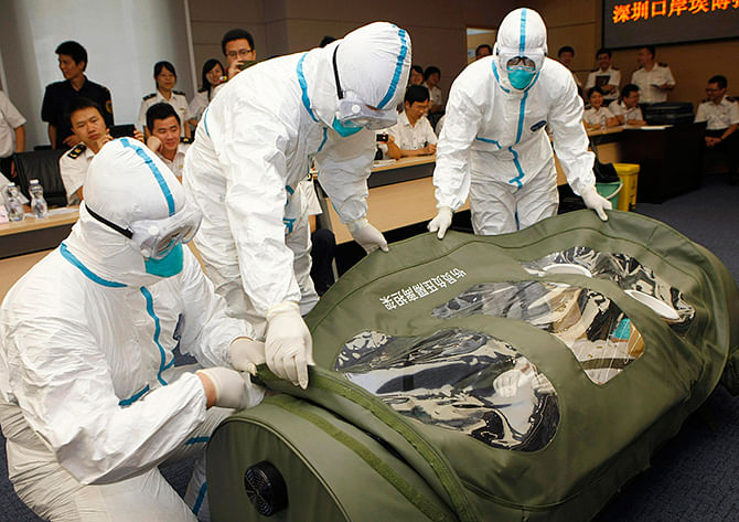 Health inspection officers help a mock patient (C) get into a negative pressure isolation stretcher, during a drill to demonstrate the procedures of transporting an Ebola victim, at Shenzhen Entry-exit Inspection and Quarantine Bureau, in Shenzhen, Guangdong province August 14, 2014. Photo: Reuters