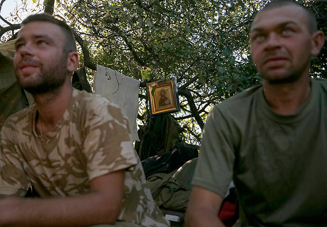 Ukrainian servicemen sit at their positions in front of a small painting near the eastern Ukrainian town of Luhansk August 26, 2014. Ukrainian President Petro Poroshenko said on Tuesday that the only effective instrument for ending bloodshed in eastern Ukraine was effective border controls with Russia, and halting arms supplies to the rebels and releasing prisoners of war. Photo: Reuters