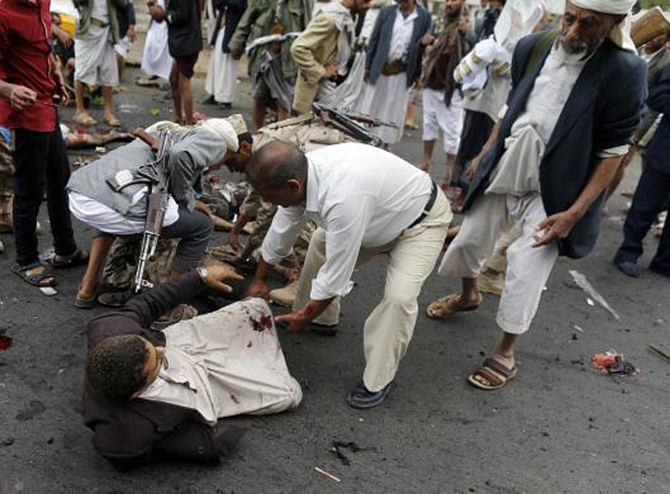 Shia Houthi rebels attempt to help a wounded man at the scene of a suicide attack in Sanaa October 9, 2014. Photo: Reuters 